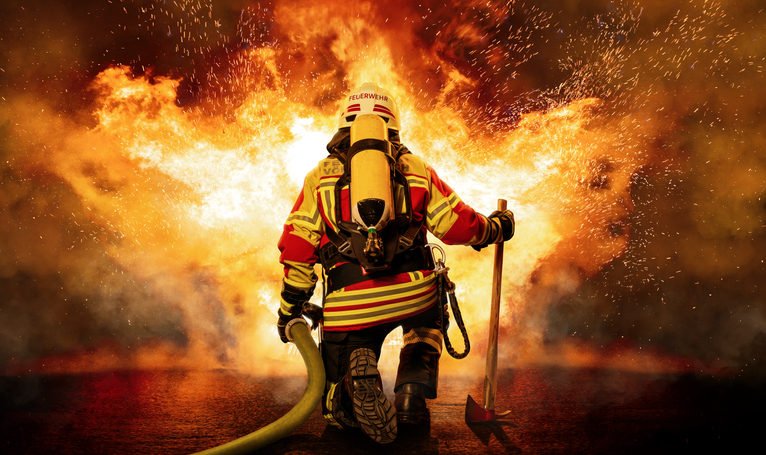 image of a fireman and a fire to illustrate emergency preparedness A fireman crouched in front of a conflagration