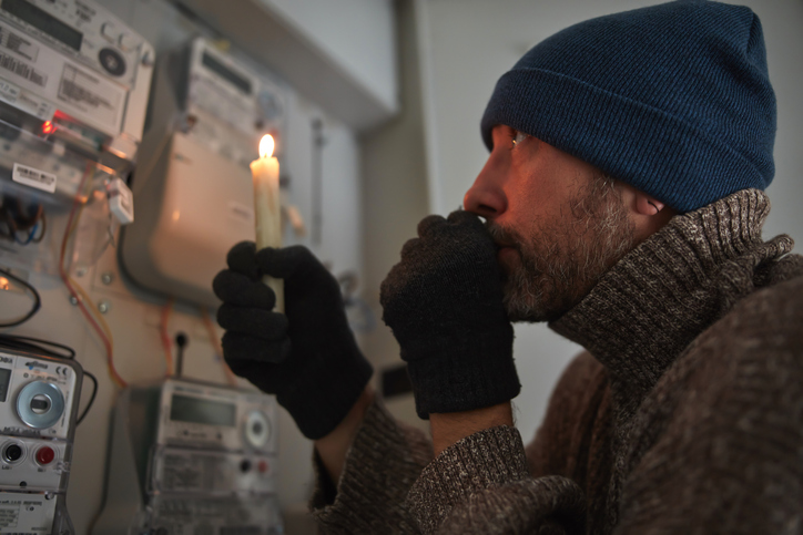 a cold guy looking at power meters with a candle