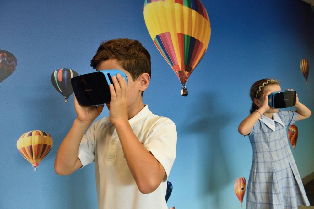 VR headsets Two children with VR headsets watch hot-air balloons flying in the sky